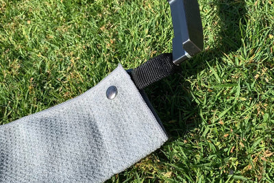 A close up image of Clothlete's gray magnetic golf towel, showing in detail its waffle-weave microfiber material. At the top of the towel is the small, magnetic golf towel attachment.