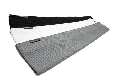 Three microfiber greenside golf towels with snaps in white, grey, and black. Each towel comes with an easy snap attachment.
